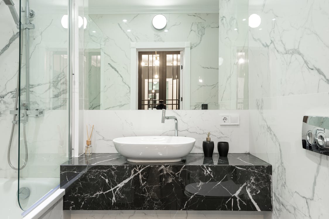 Bathroom vanity with a dark veined countertop, white vessel sink, and wall-mounted faucet